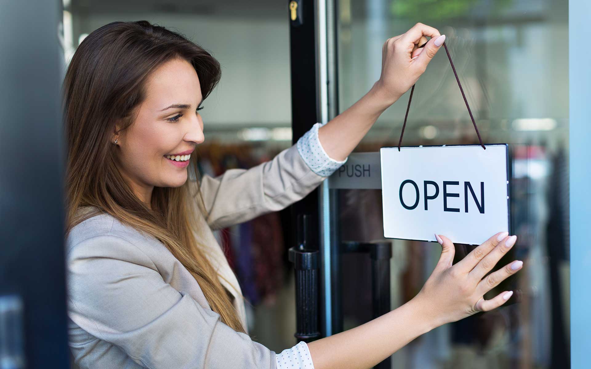 Female hanging an open sign on shop door